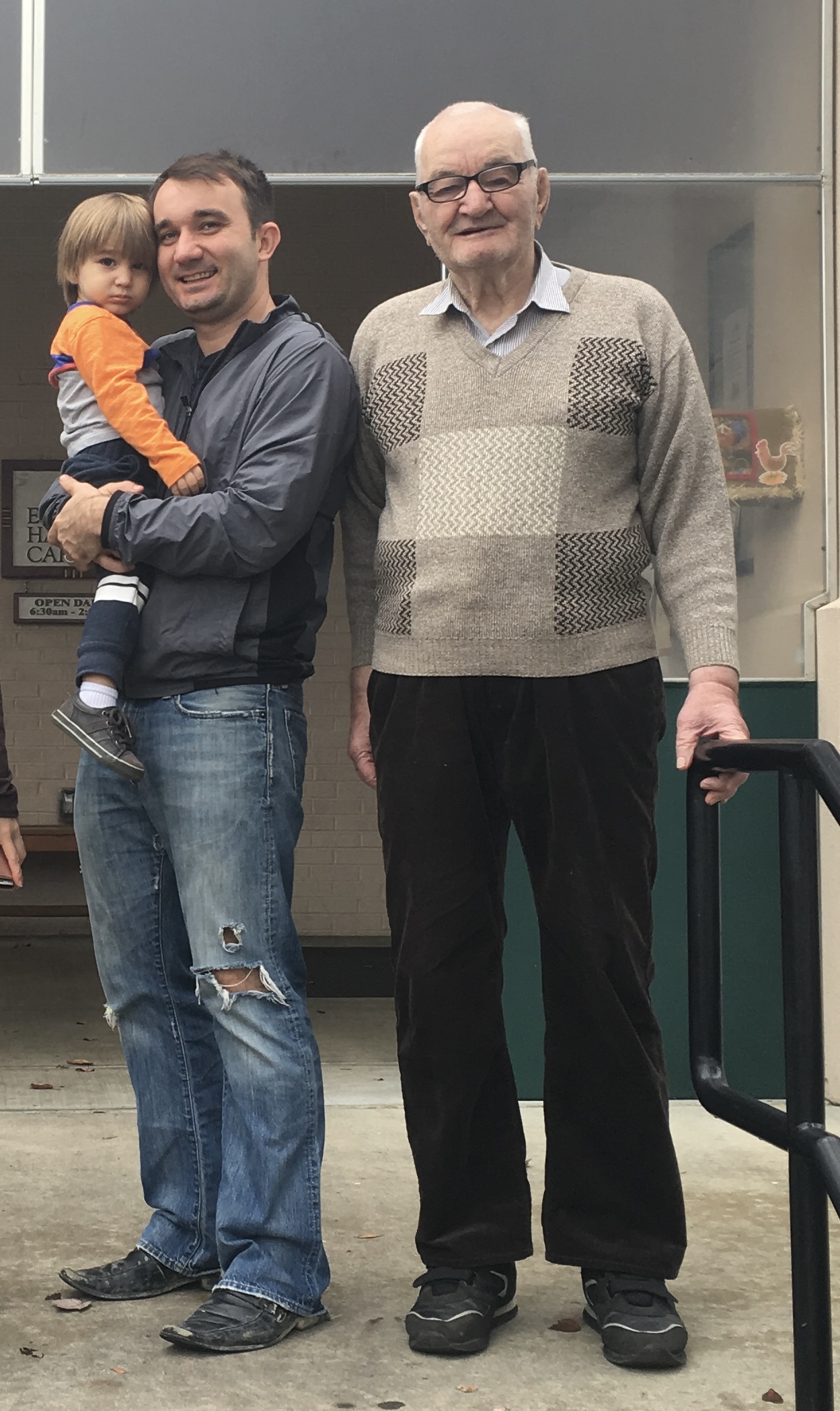 Grandson holding his young child beside his grandfather